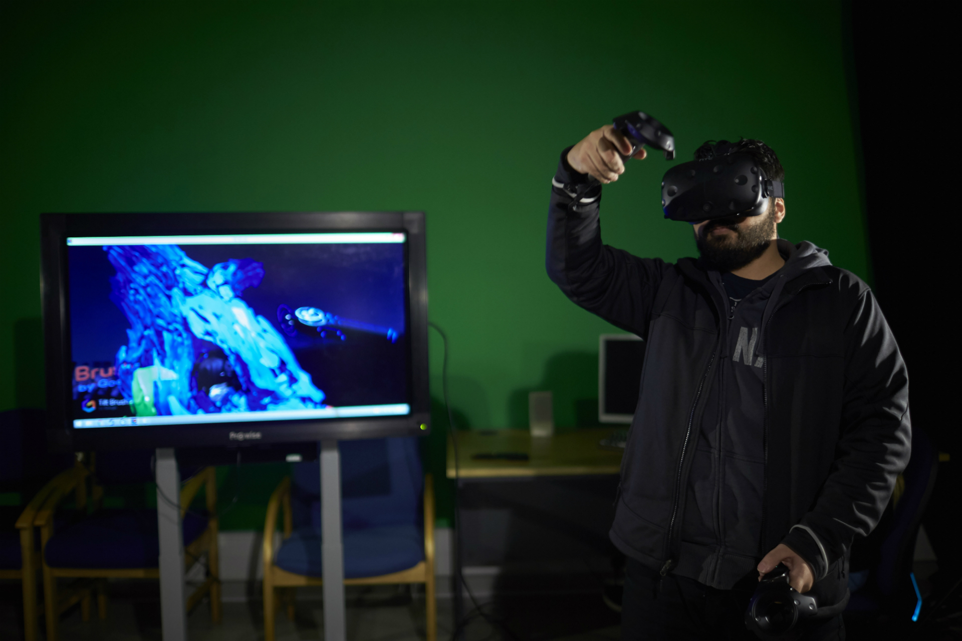 Male wearing Virtual Reality head - display screen in background