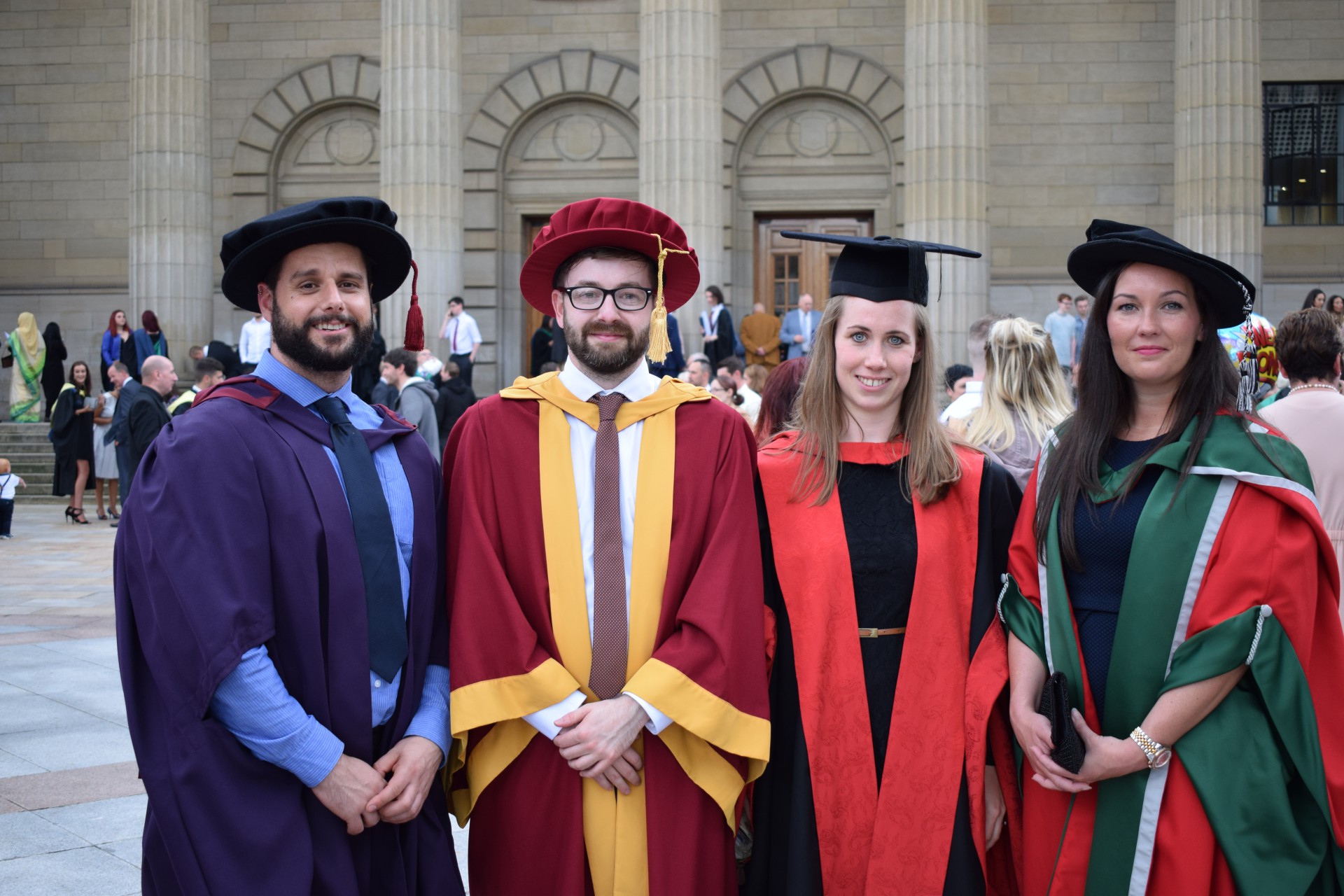 Four post graduate students wearing graduation gowns