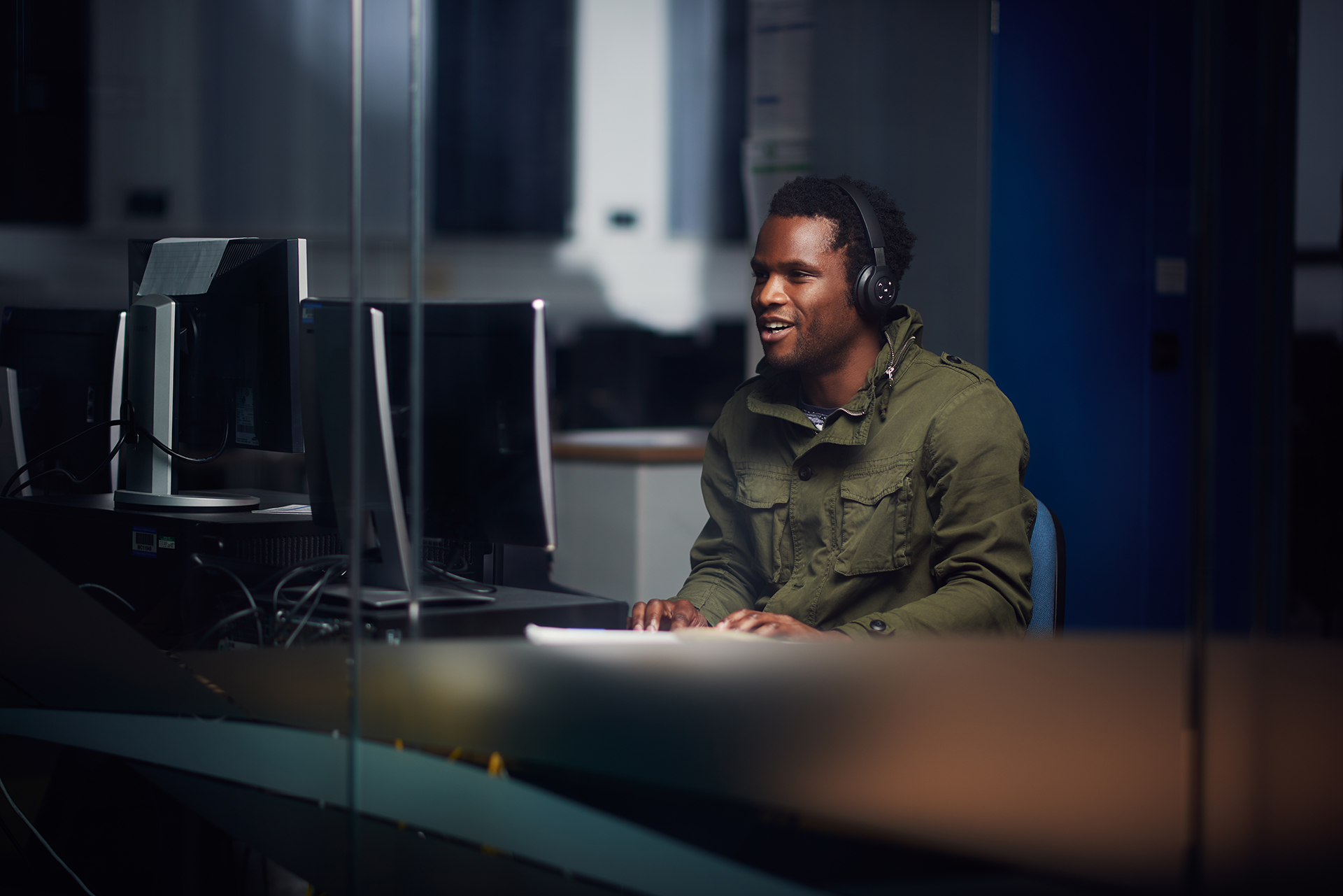 Male student wearing headphones whilst working on a Desktop computer