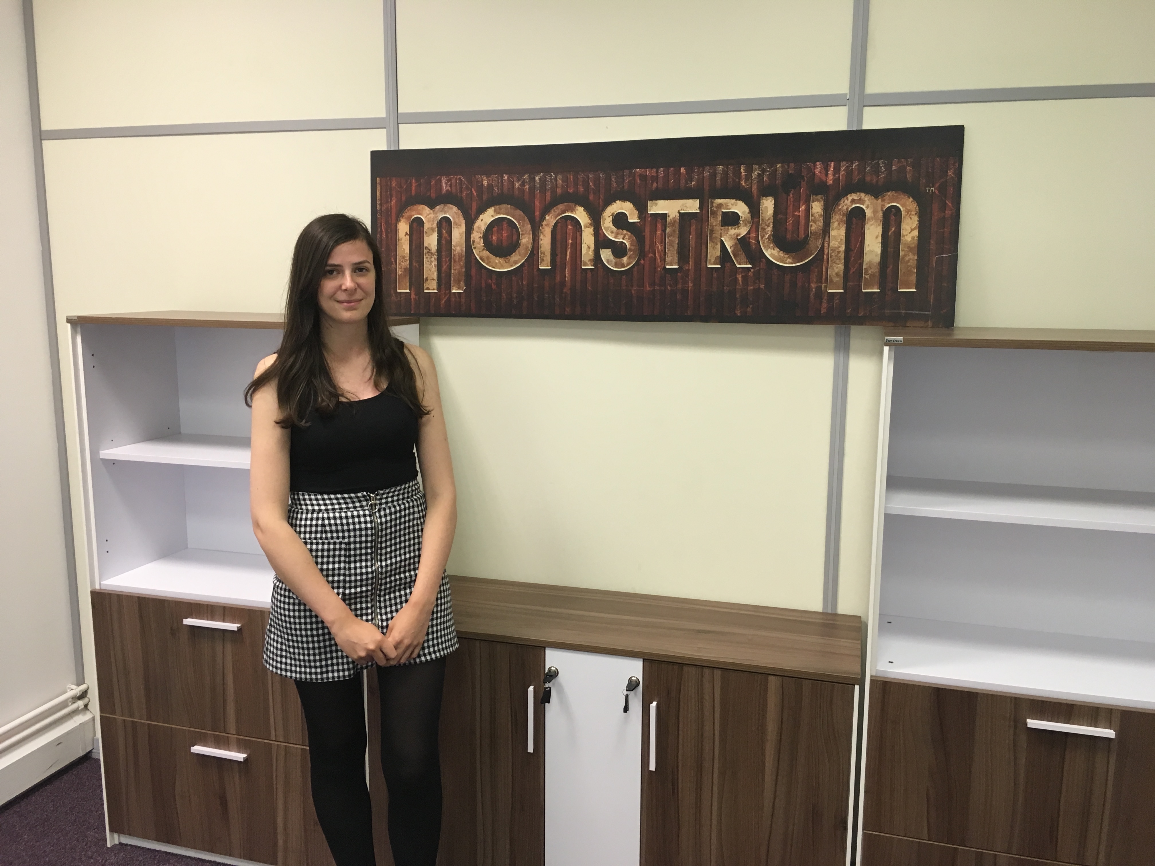 A picture of Stephanie Bayzeley by the logo for the game Monstrum
