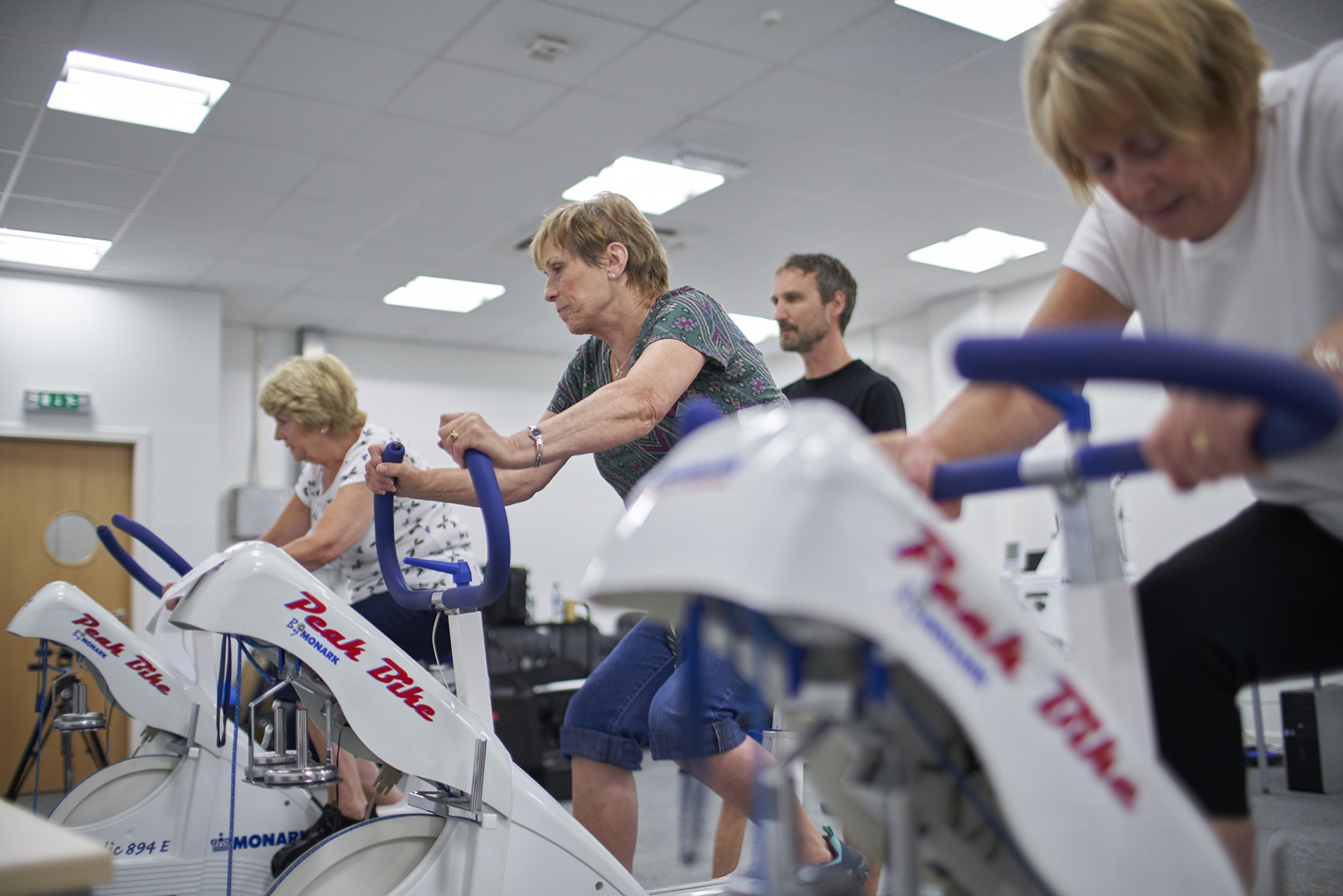 A photo of three elderly women on exercise bikes