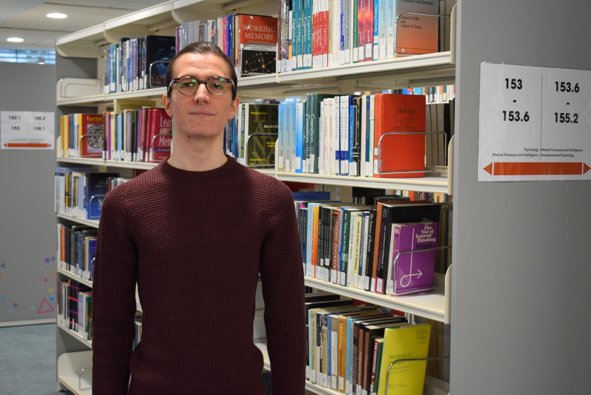 A photo of Nikolay Panayotov in Abertay University library, in front of bookshelves