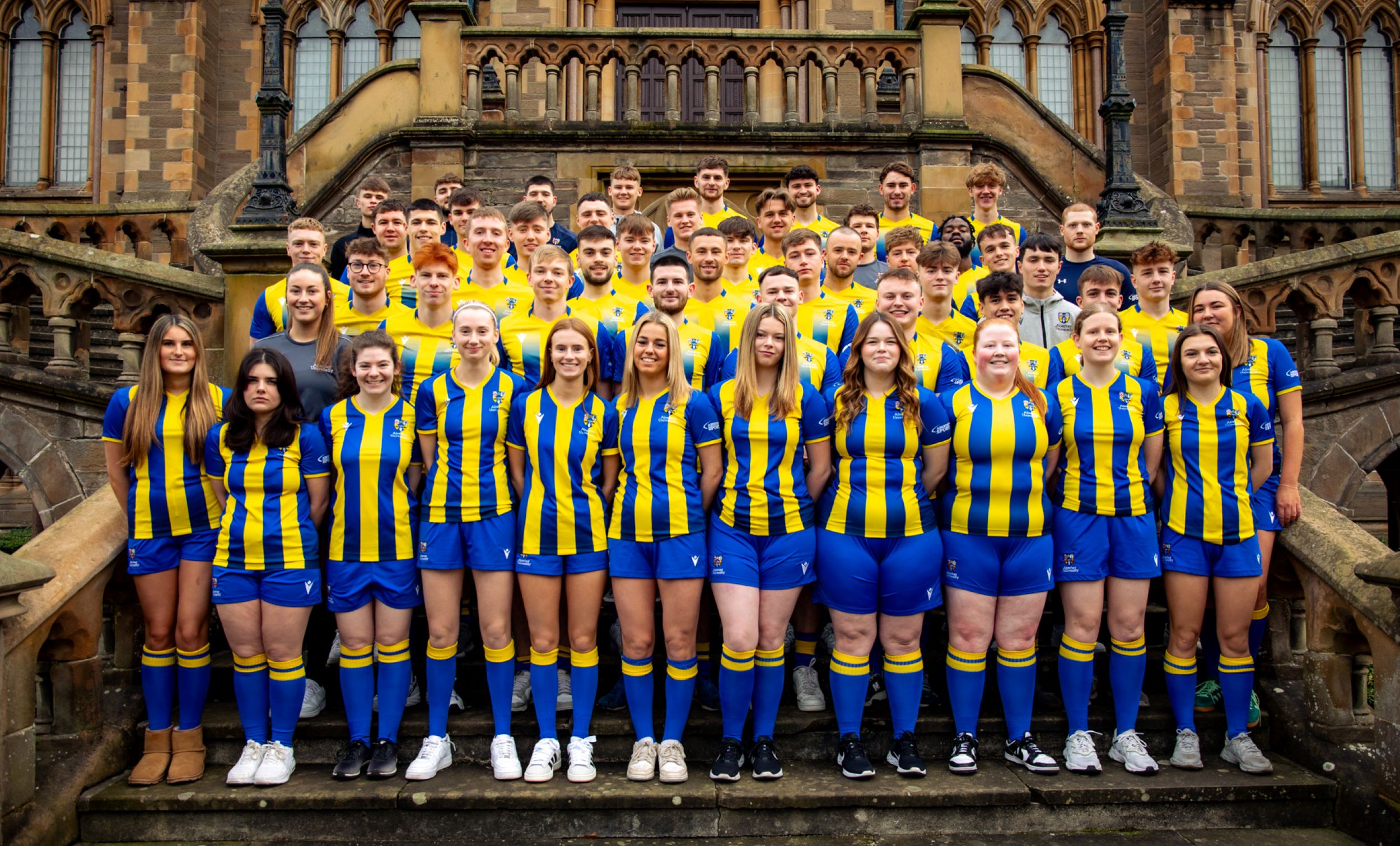 Mixed football teams standing on steps outside McManus library