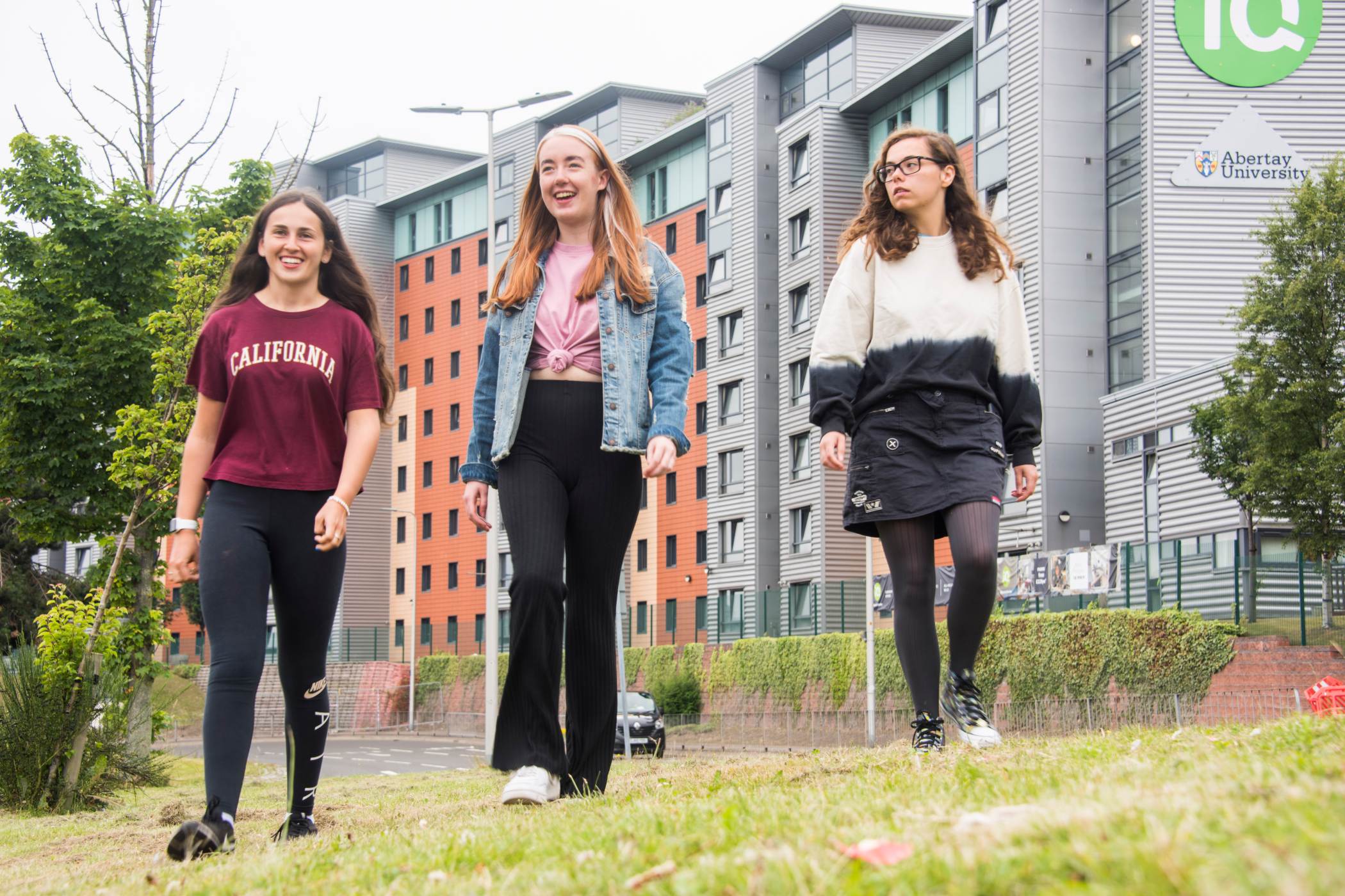 Three female students walking beside Parker House