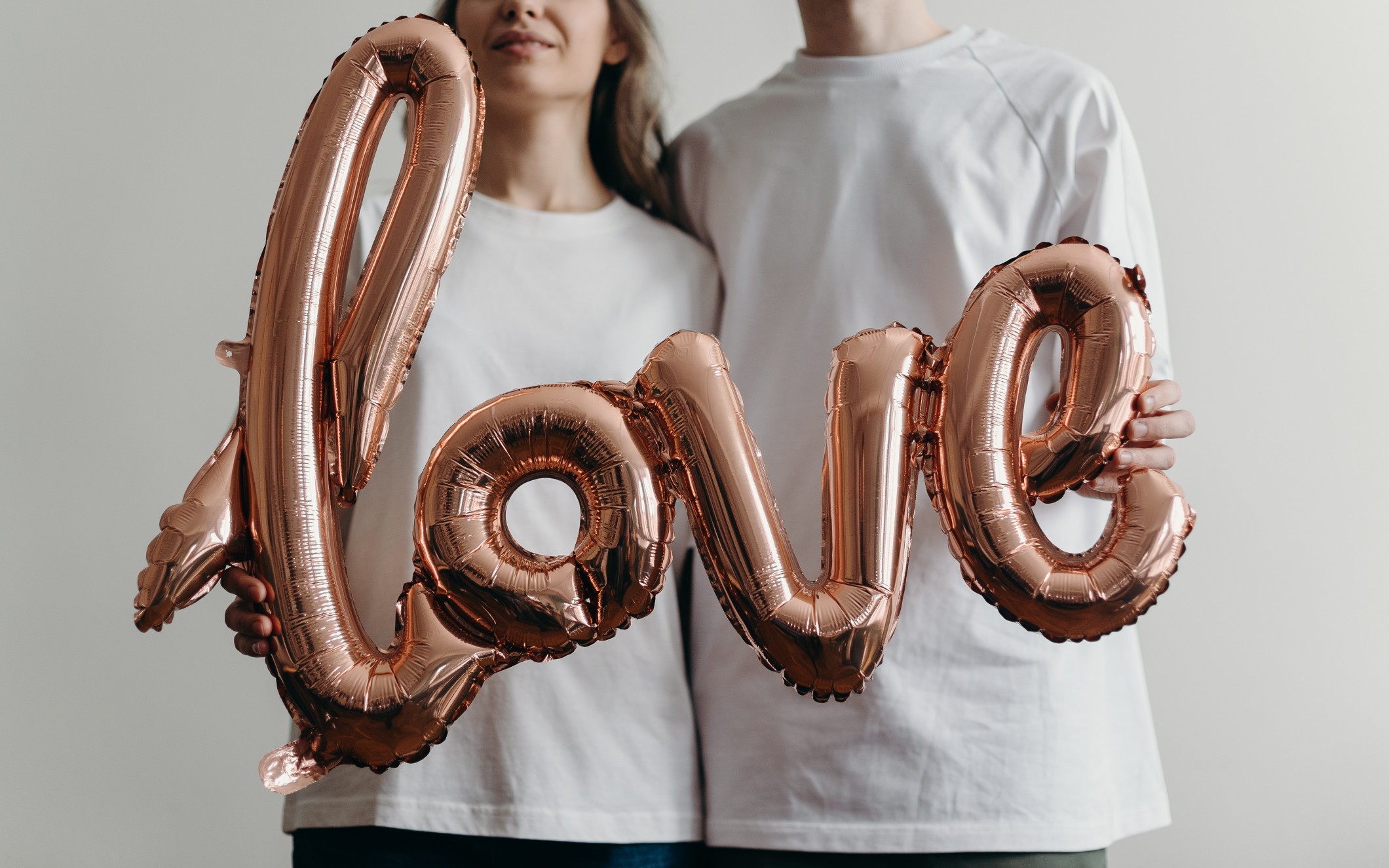 A woman on the left and a man on the right are holding a balloon that reads "love"